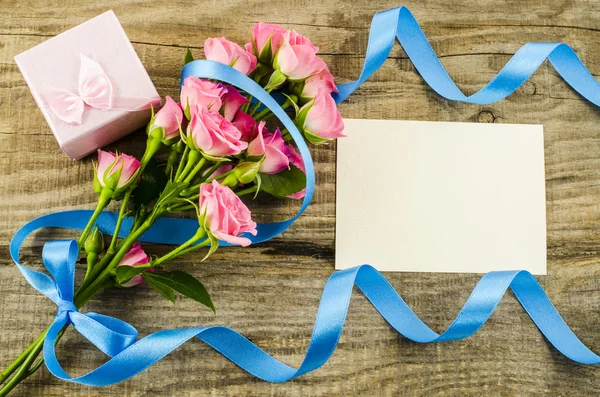 Tarjeta postal vacía, flor y cinta azul sobre fondo de madera — Foto de Stock