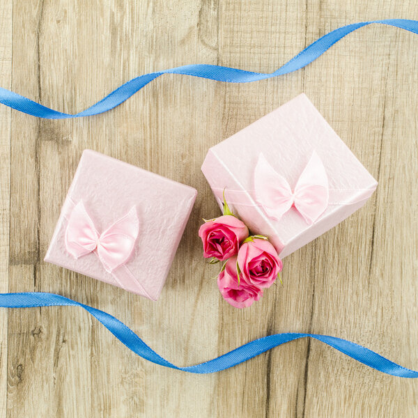 Gift box with rose flower, heart and ribbon on wooden background