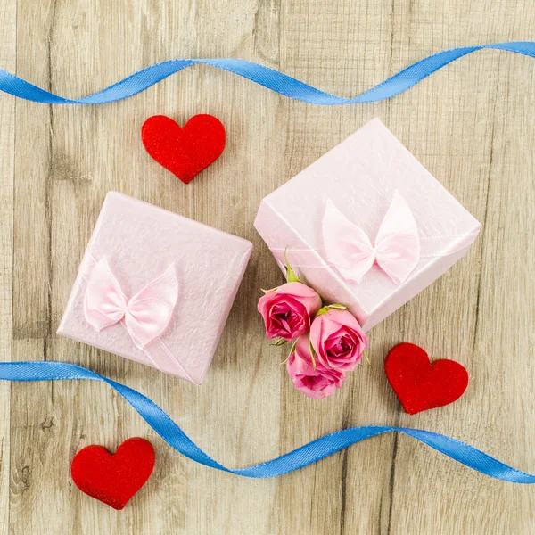 Confezione regalo con fiore di rosa, cuore e nastro su fondo di legno — Foto Stock