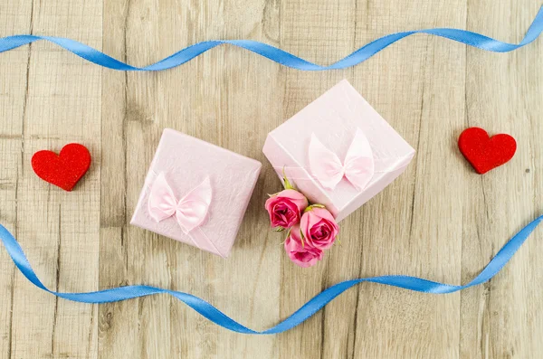 Confezione regalo con fiore di rosa, cuore e nastro su fondo di legno — Foto Stock