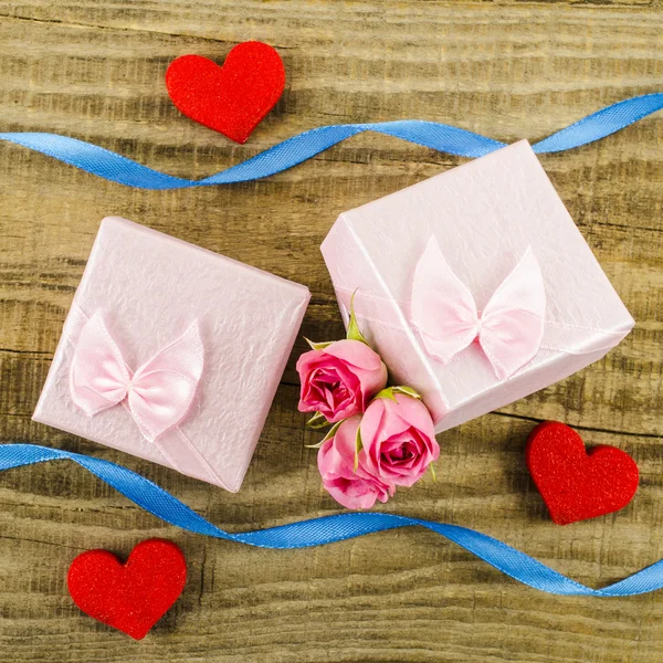 Caja de regalo con flor rosa, corazón y cinta sobre fondo de madera — Foto de Stock