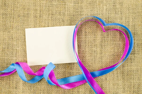 Empty card with heart shaped ribbon on linen background — Stock Photo, Image