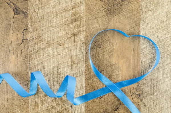 Heart shaped ribbon on wooden background — Stock Photo, Image