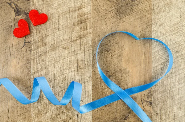 Heart shaped ribbon on wooden background — Stock Photo, Image