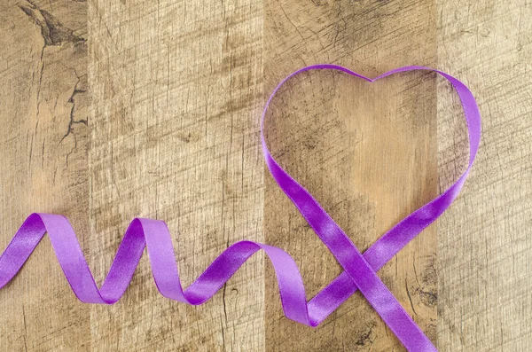 Heart shaped ribbon on wooden background — Stock Photo, Image