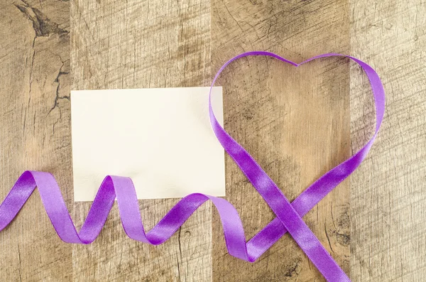 Empty card with heart shaped ribbon on wooden background — Stock Photo, Image