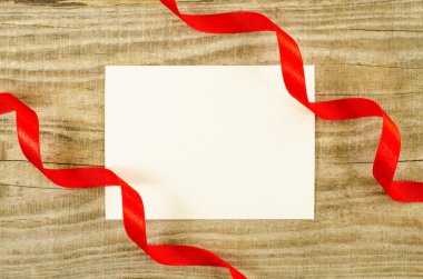Ahşap arka plan üzerinde kırmızı kurdele ile boş oyun kağıdı