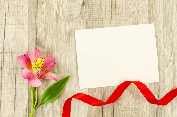 Tarjeta vacía, flor y cinta roja sobre fondo de madera —  Fotos de Stock