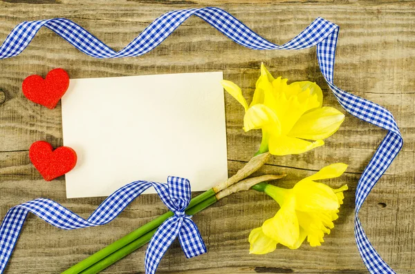 Empty card with flower and ribbon on wooden background