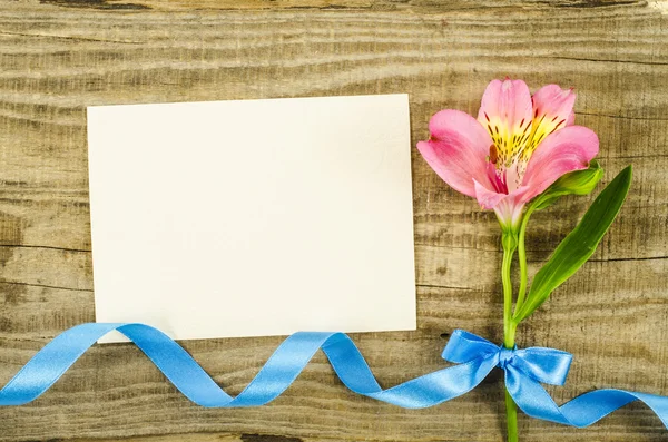 Tarjeta vacía con flor y cinta sobre fondo de madera — Foto de Stock