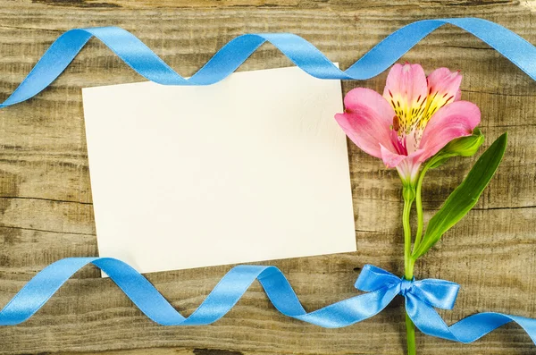 Tarjeta vacía con flor y cinta sobre fondo de madera —  Fotos de Stock