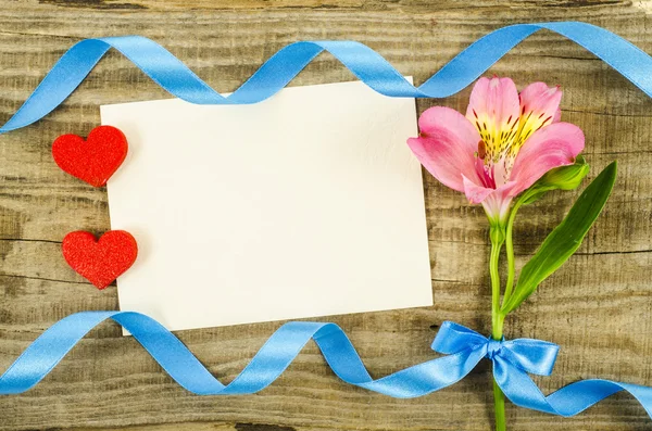 Empty card with flower and ribbon on wooden background — Stock Photo, Image