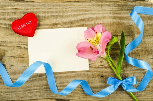 Bunte Blume mit Schleife und leerer Karte auf Holztisch — Stockfoto