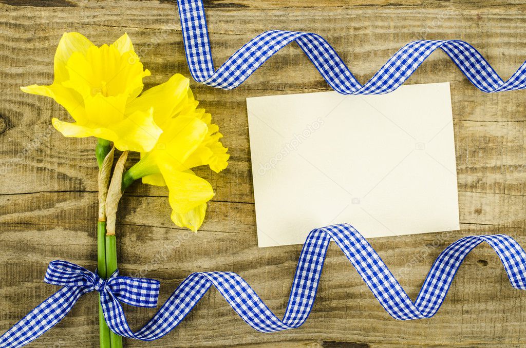 Empty card with flower and ribbon on wooden background