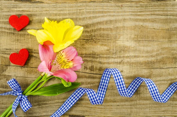 Kwiat z niebieską wstążką na drewnianym stole — Zdjęcie stockowe
