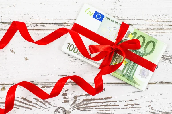 Billete de cien euros con cinta roja sobre mesa de madera — Foto de Stock