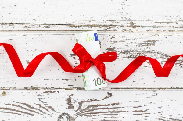 Hundred euro bill with red ribbon on wooden table — Stock Photo, Image