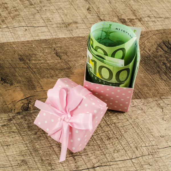 Gift box full of money on wooden table — Stock Photo, Image