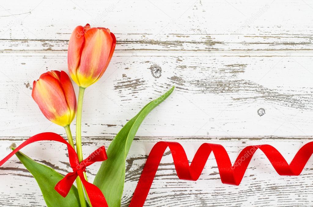 Empty wooden background with colorful flowers and red ribbon