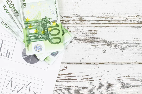 Grafikler ve ahşap masa üzerinde para — Stok fotoğraf