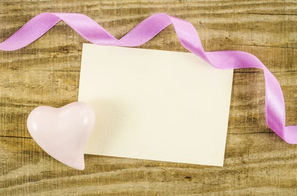 Empty card with heart and ribbon on wooden table — Stock Photo, Image