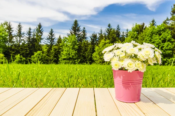 Kbelík plný květin na dřevěný stůl — Stock fotografie
