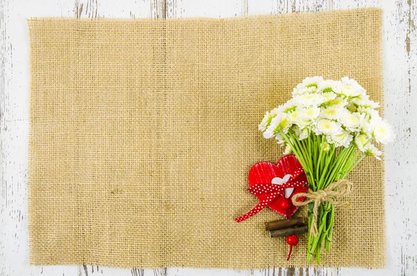 Flores com coração sobre fundo de juta — Fotografia de Stock