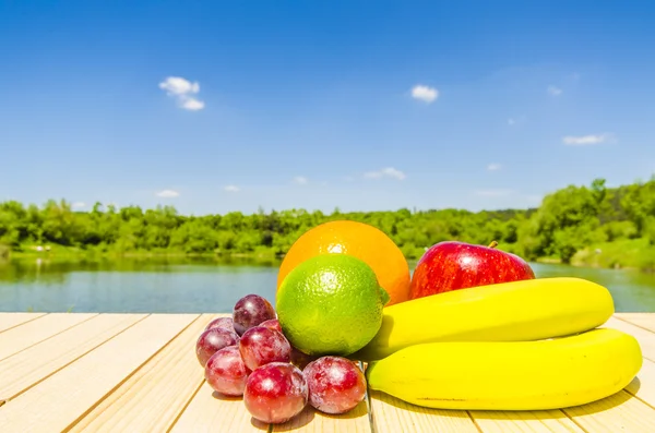 Färsk frukt på träbord med landskap bakgrund — Stockfoto