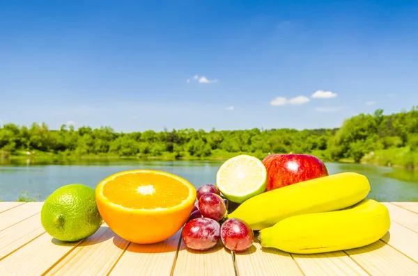 Färsk frukt på träbord med landskap bakgrund — Stockfoto