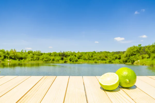 Limes em mesa de madeira com fundo de paisagem — Fotografia de Stock