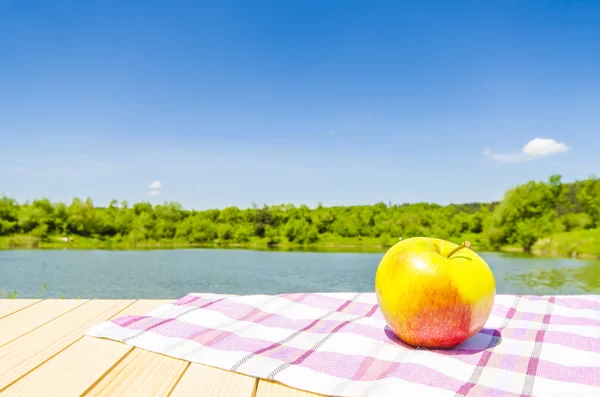 Äpple på träbord med landskap bakgrund — Stockfoto