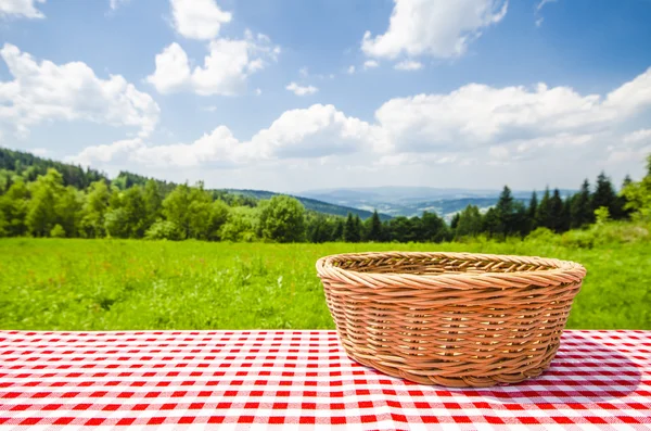 Empty table with wicker basket and landscape background — Stock Photo, Image