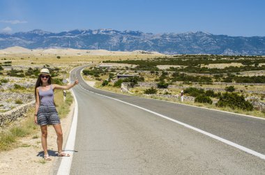 Genç kadın boş yolda otostop