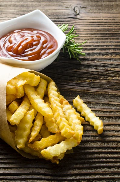 Batatas fritas com ketchup na velha mesa de madeira — Fotografia de Stock