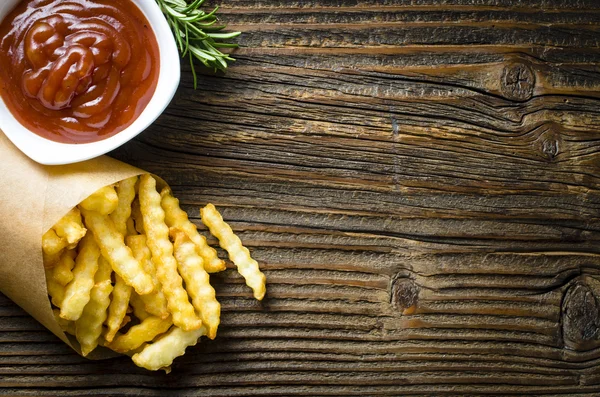 Franse frietjes over oude houten tafel — Stockfoto