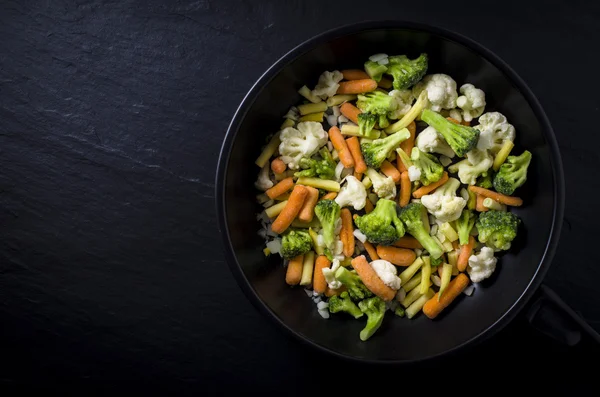 Frozen vegetables in black frying pan — Stock Photo, Image