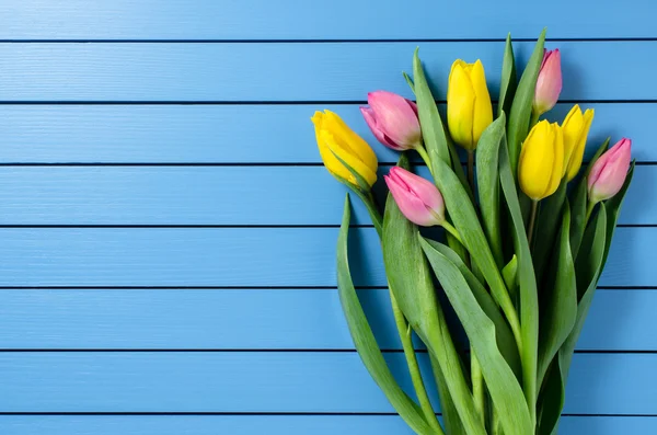 Tulipanes coloridos sobre mesa de madera azul — Foto de Stock