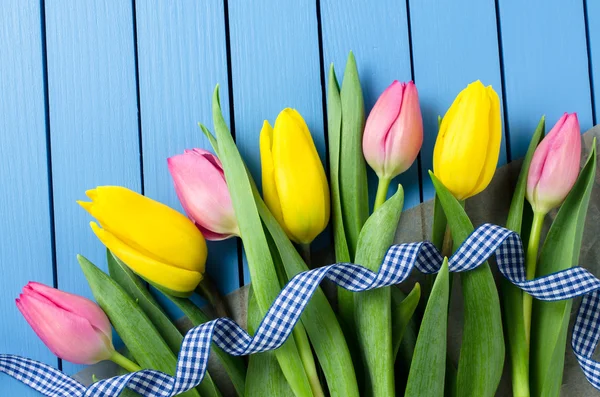 Tulipanes coloridos sobre mesa de madera azul — Foto de Stock