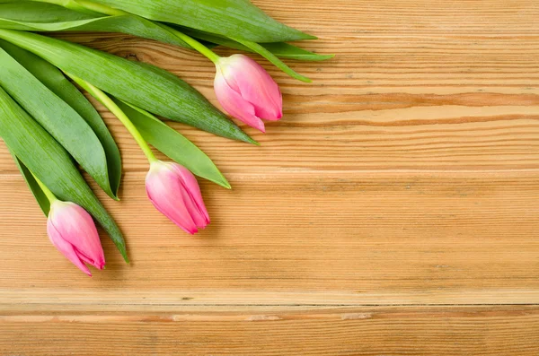 Tulipas cor-de-rosa em uma velha mesa de madeira — Fotografia de Stock