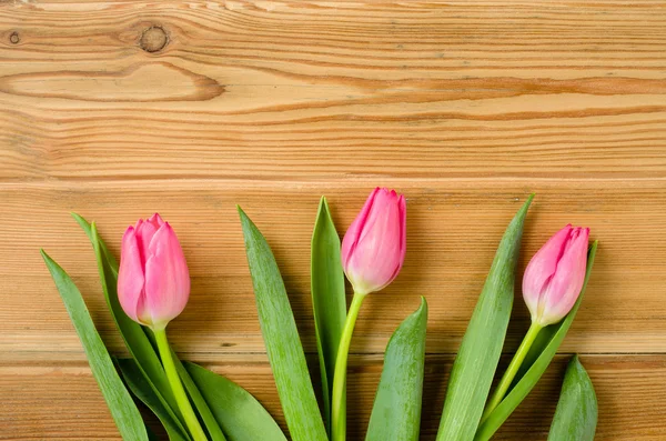 Tulipas cor-de-rosa em uma velha mesa de madeira — Fotografia de Stock