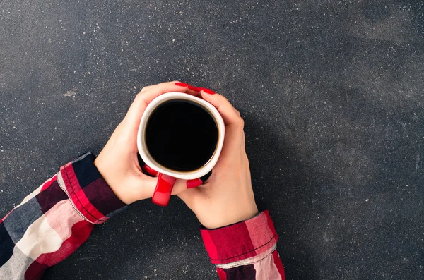 Mãos femininas segurando xícara de café sobre mesa escura — Fotografia de Stock