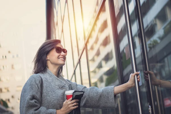 Gülümseyen kadın binaya giriyor. Mutlu iş kadını işe gidip ofise giriyor..