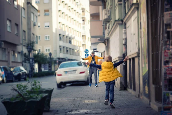 路上で父の方に腕を伸ばした幸せな少年 父と息子が街に集まる — ストック写真