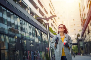 Gülümseyen modaya uygun bir kadın alışveriş caddesinde yürüyor.. 