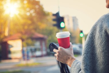 Tek kullanımlık kahve bardağıyla karşıdan karşıya geçen kadın. Şehirde kahve içen tanınmayan bir kadın.. 