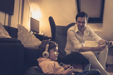 Mutlu adam ve oğlu evde birlikte vakit geçirirken video oyunu oynuyorlar..