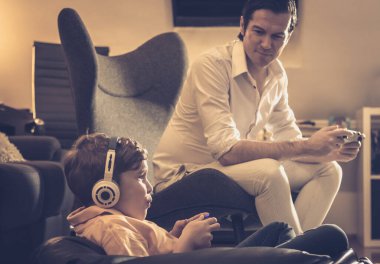 Baba ve oğul evde dinlenirken video oyunu oynuyorlar. Çocuğa odaklan.. 