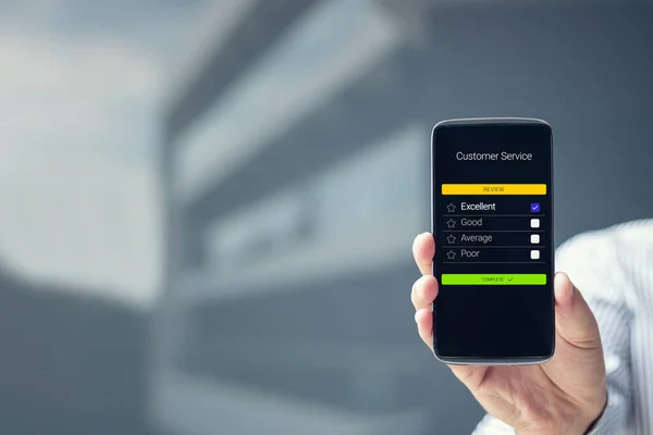 İş adamı müşteri hizmetlerini akıllı telefondan değerlendiriyor. Online değerlendirme değerlendirme derecesi telefonda. Müşteri memnuniyeti kavramı.