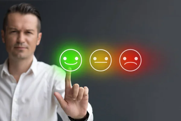 Dijital dokunmatik ekranda gülen surat ifadesine basan adam. Müşteri hizmetleri değerlendirme kavramı.