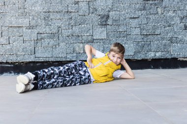 Gülümseyen çocuk yere yatıp kameraya bakarken eğleniyor. Boşluğu kopyala. 